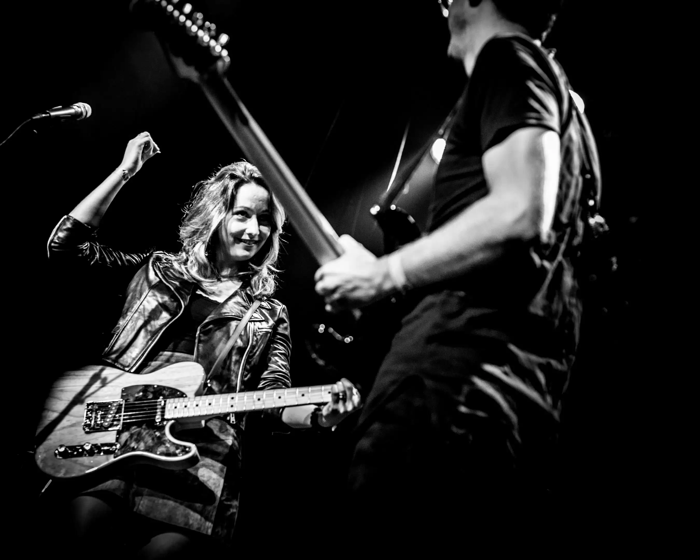 Docent Muziek Lisanne staat op het podium met haar gitaar. De foto is zwart wit.