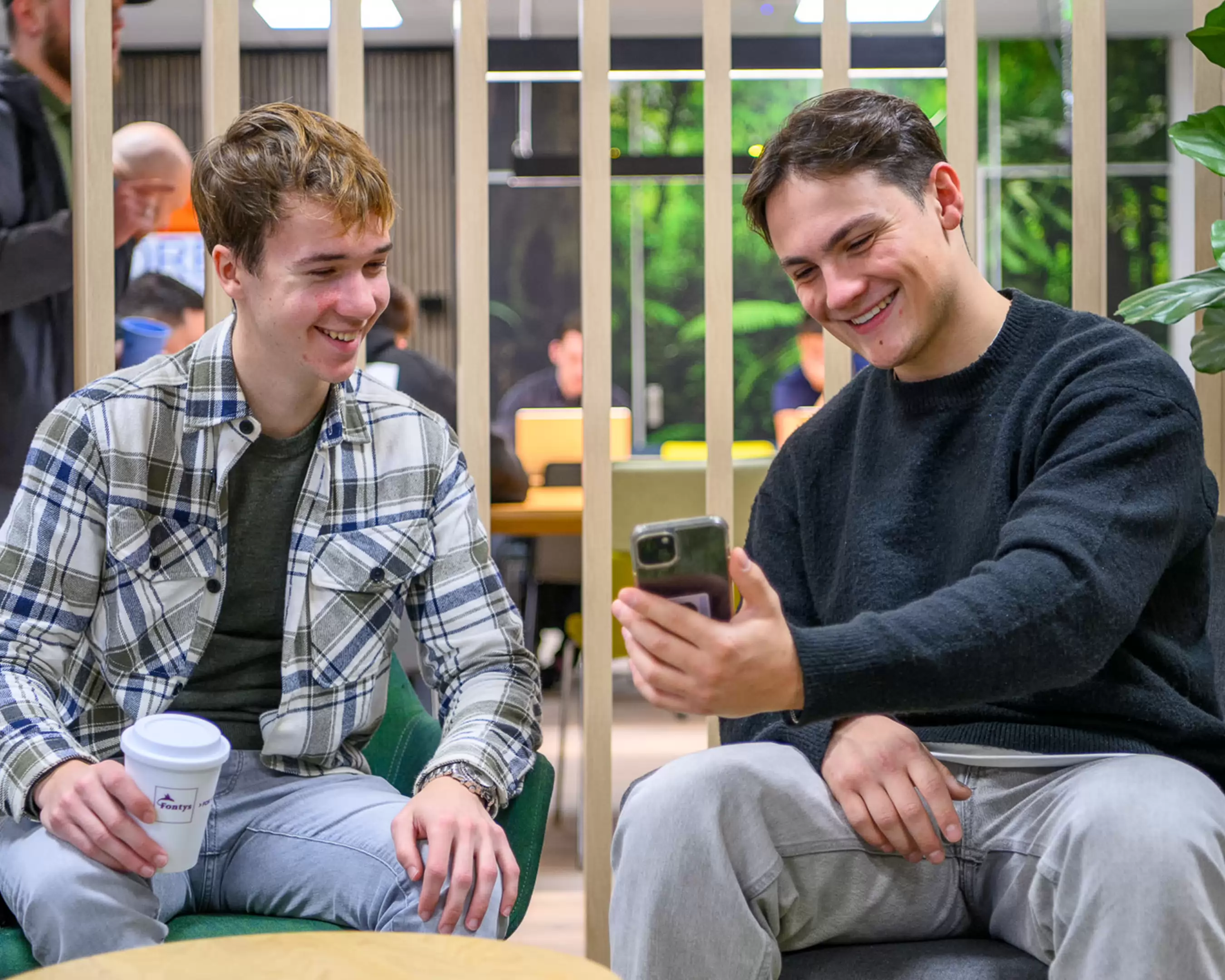 Twee Finance, Tax and Advice studenten die elkaar iets laten zien op hun telefoon.