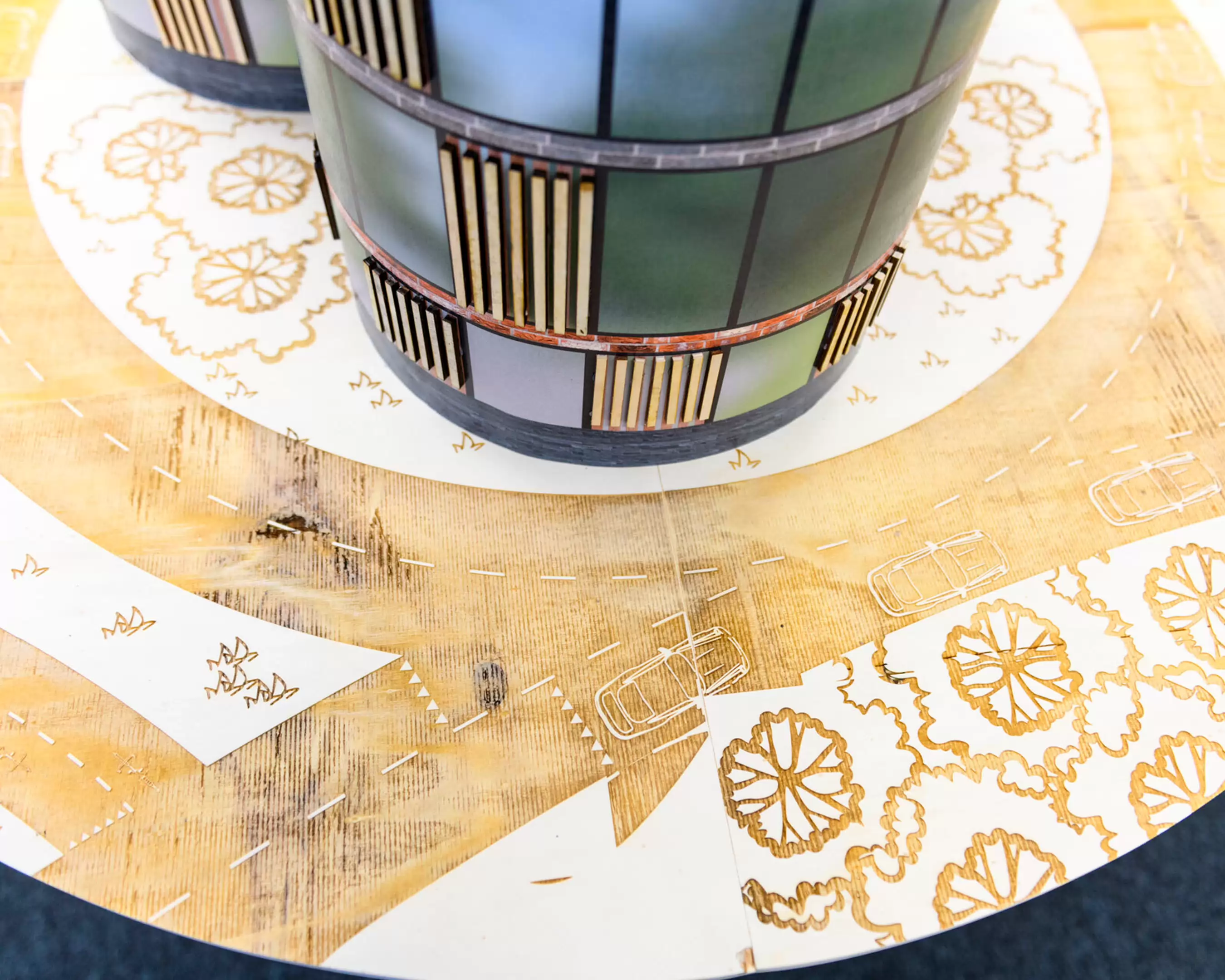 Detail van een maquette met ronde gebouwen en een plattegrond met wegen en bomen.