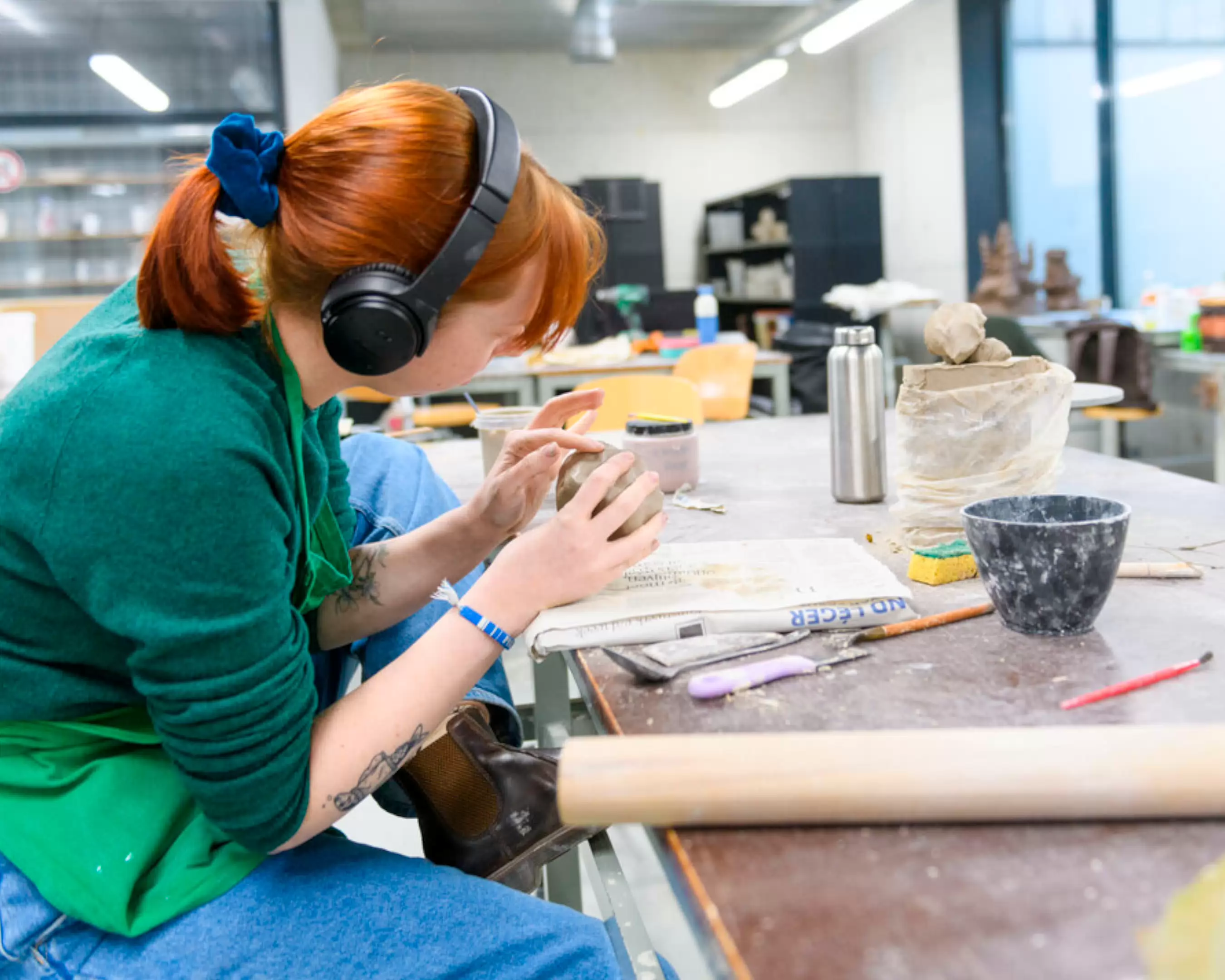 Student werkt geconcentreerd aan een kleiwerkstuk in een atelier.