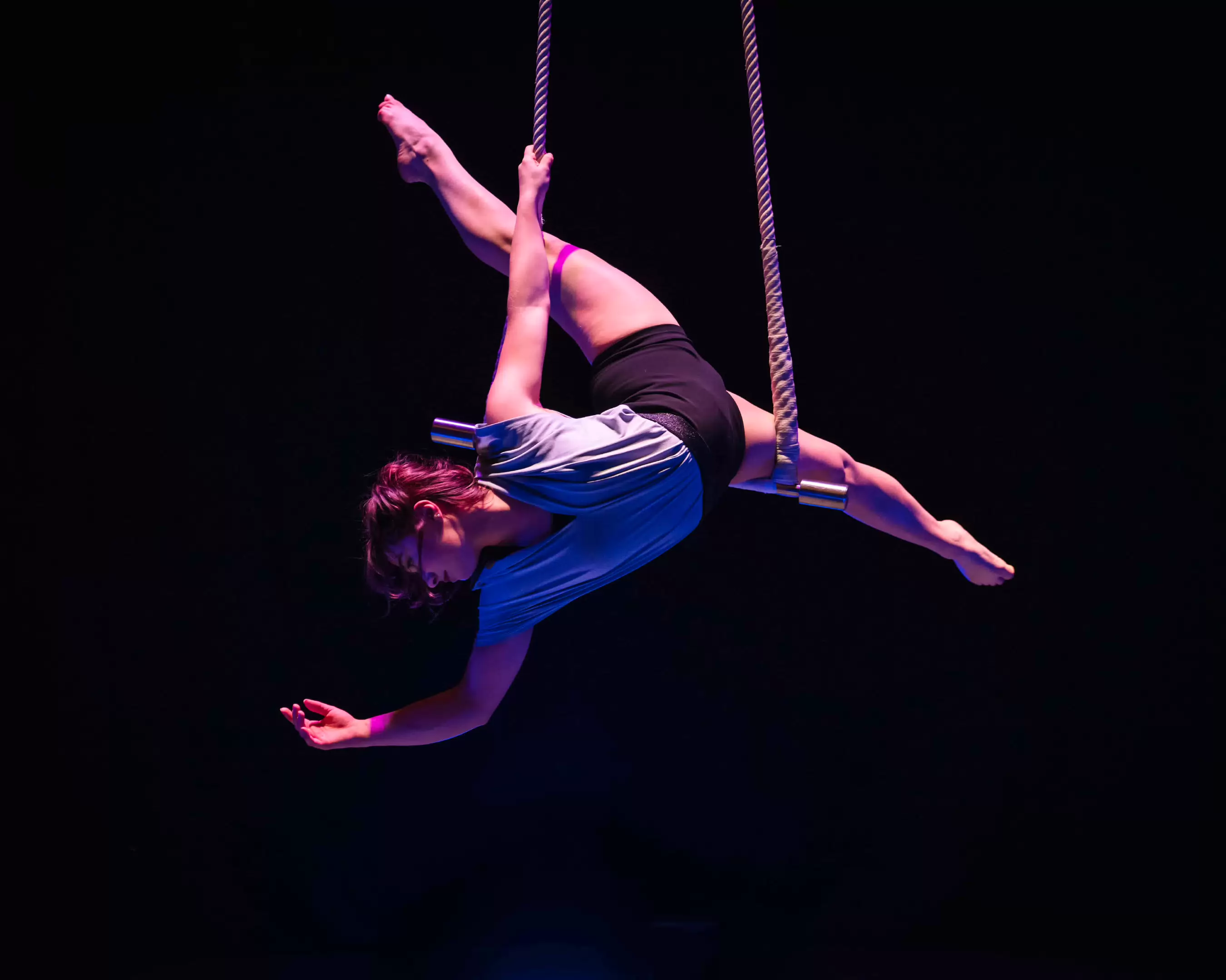 A circus student is performing an act on the trapeze