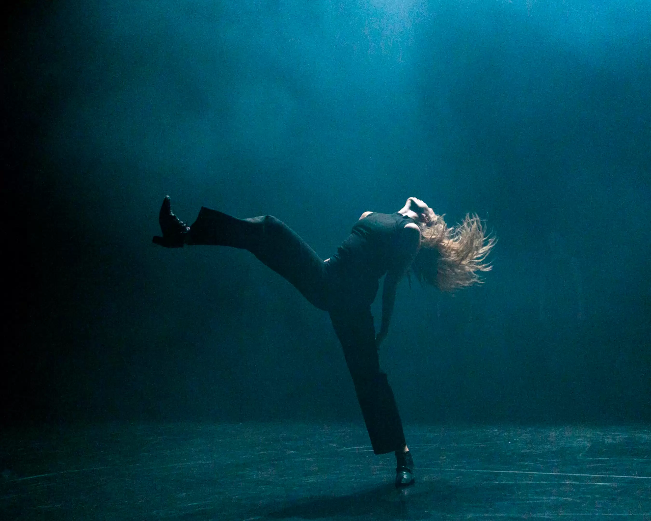 A student is dancing on stage, in blue light and smoke