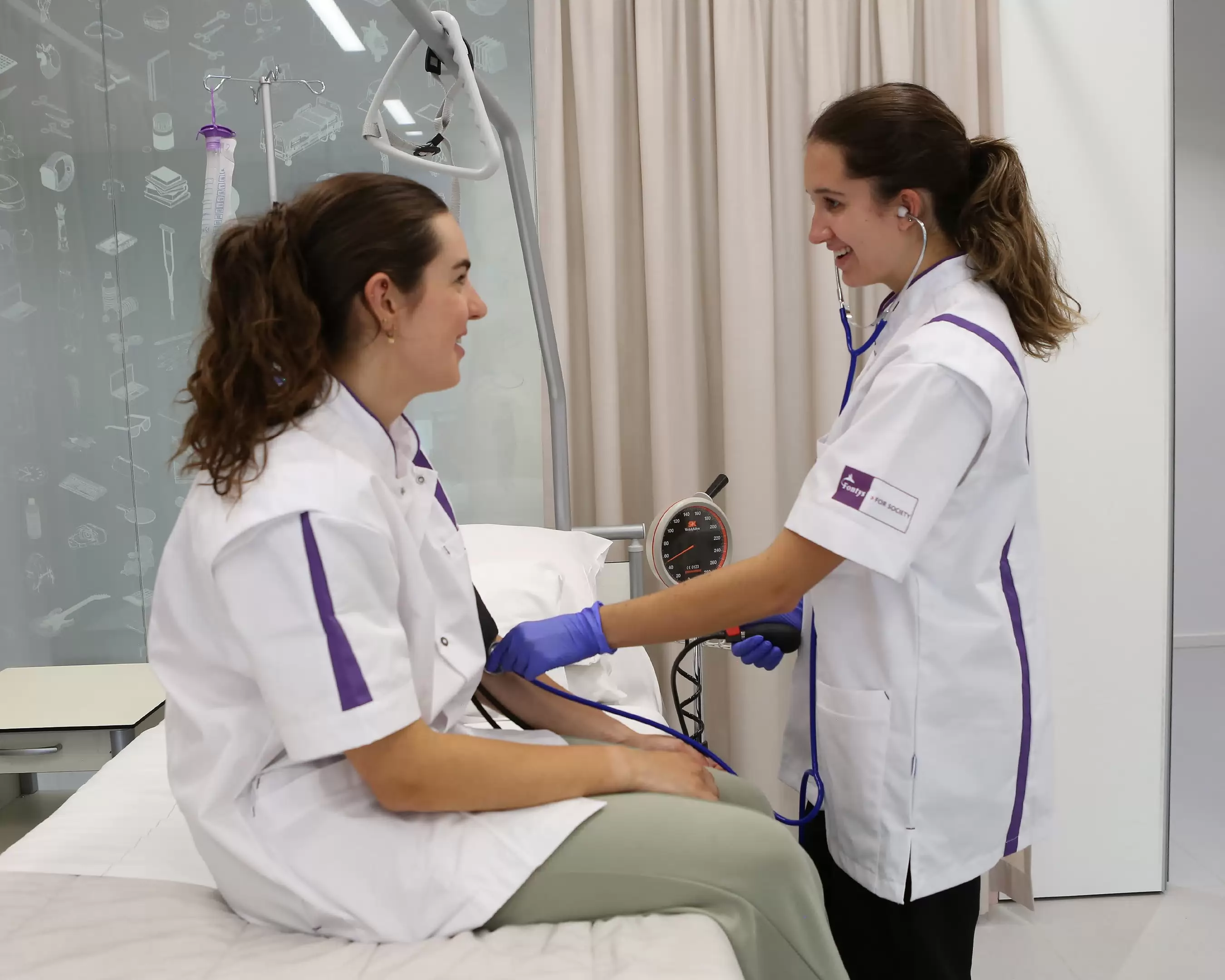 Studenten van de opleiding Verpleegkunde in een werksituatie aan een tafel met een dossier.
