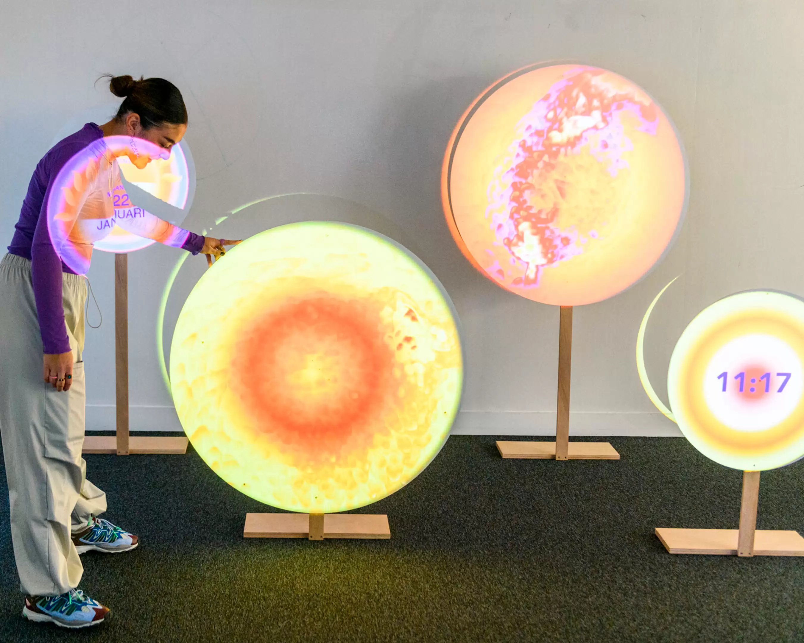 Jongere bekijkt interactieve, ronde lichtobjecten met kleurrijke projecties.