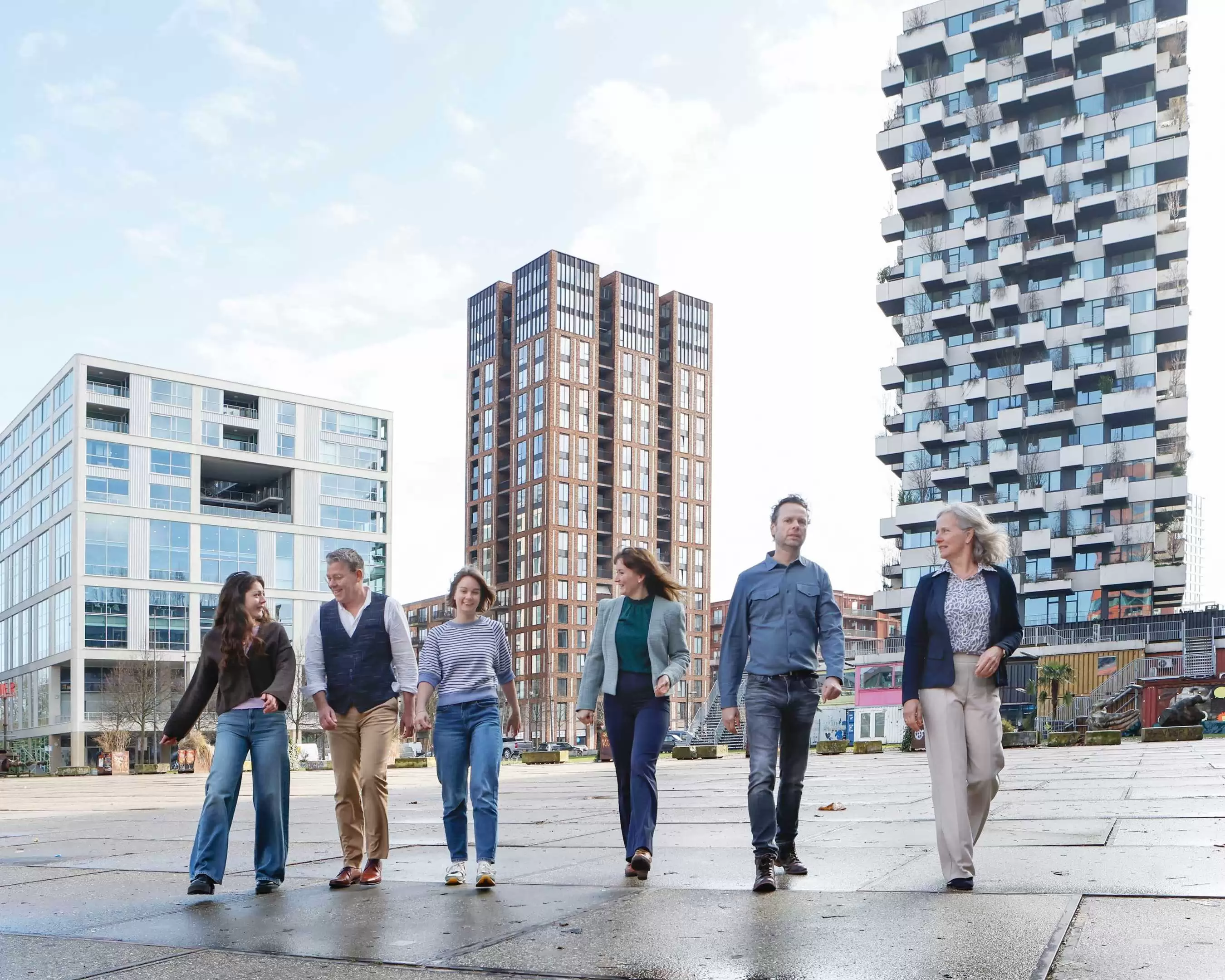 Een groep professionals op een plein met grote gebouwen op de achtergrond
