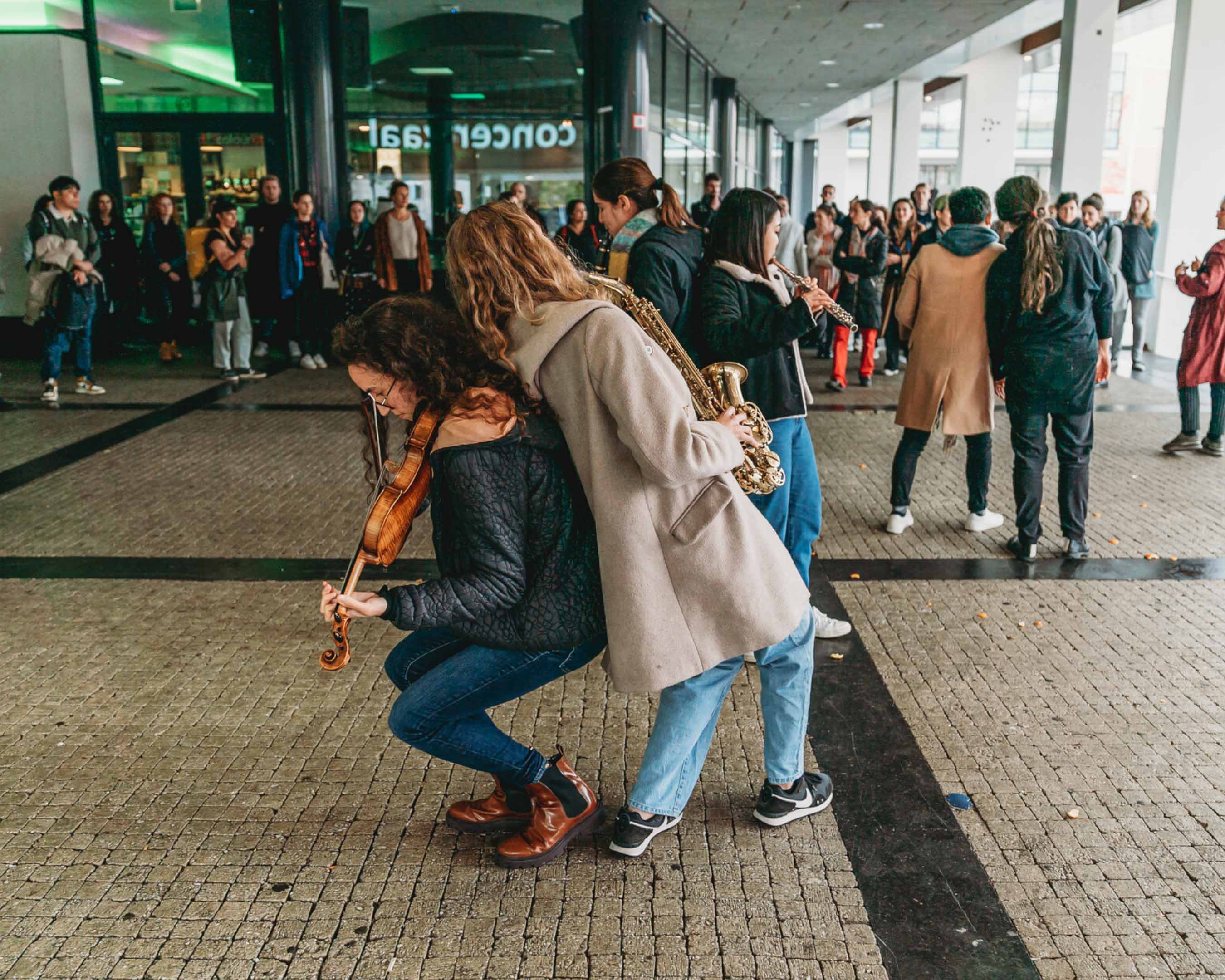 students perform outdoors with instruments such as violin. flute and saxophone