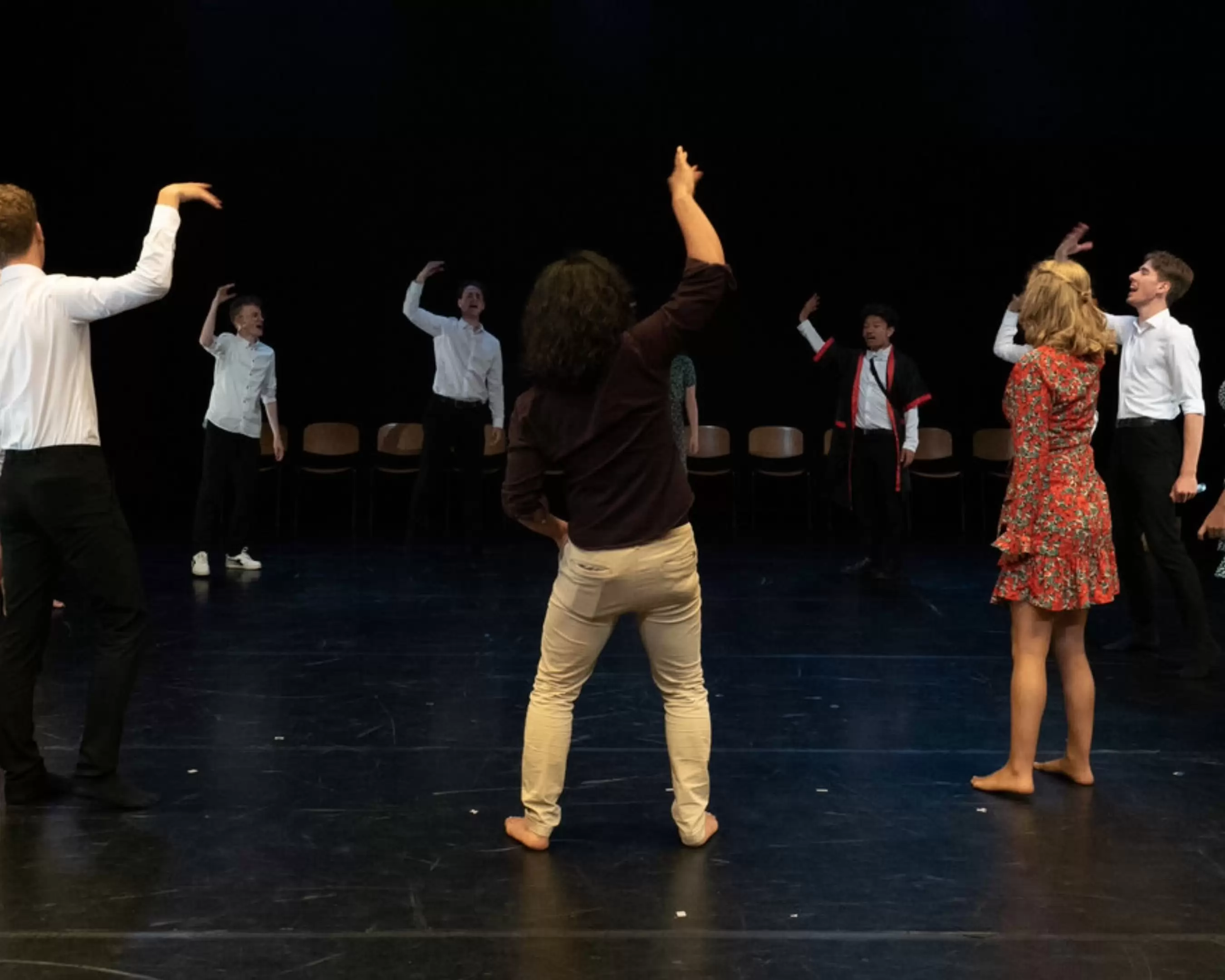 Jongeren doen een theaterspel in een kring op het podium.