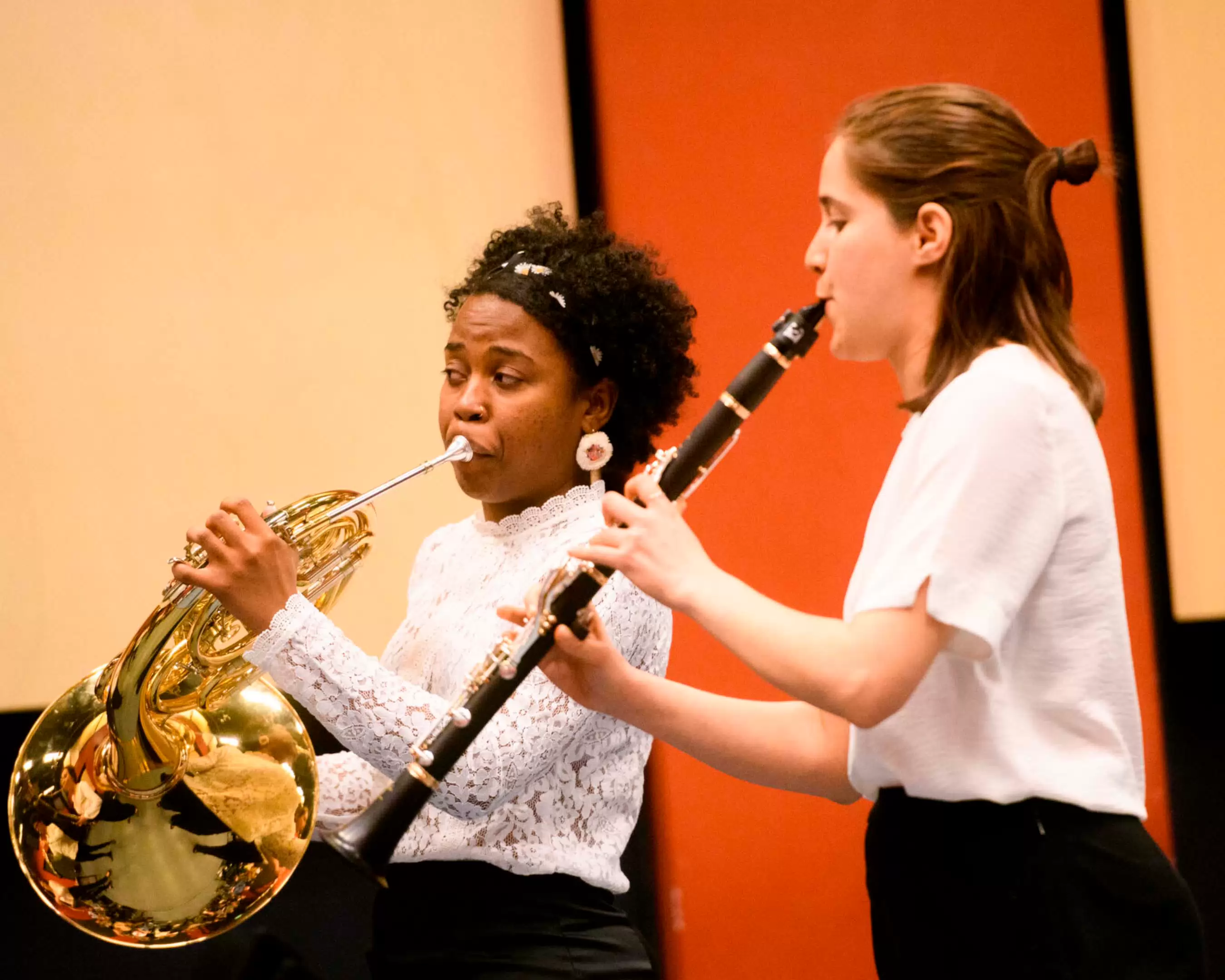 Two students of the conservatory of music are performing with horn and clarinet