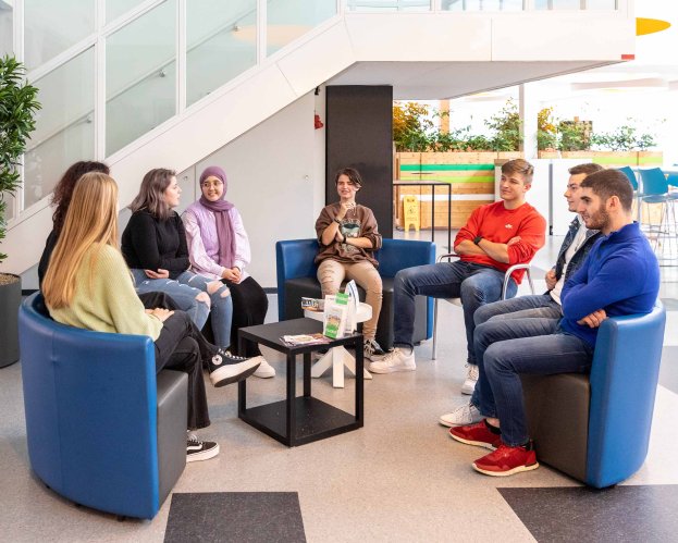 Groepje studenten opleiding Leraar Omgangskunde in gesprek in stoelen op de gang
