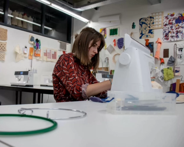 Student achter naaimachine in textielwerkplaats