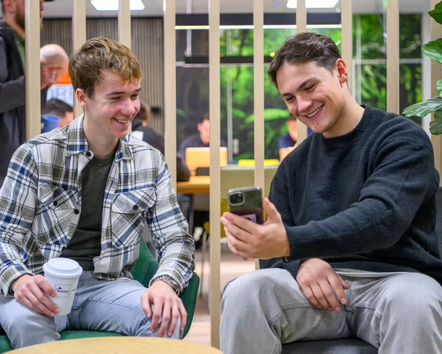 Twee Finance, Tax and Advice studenten die elkaar iets laten zien op hun telefoon.