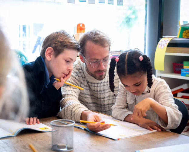 Een leraar werkt met een groepje kinderen aan een opdracht