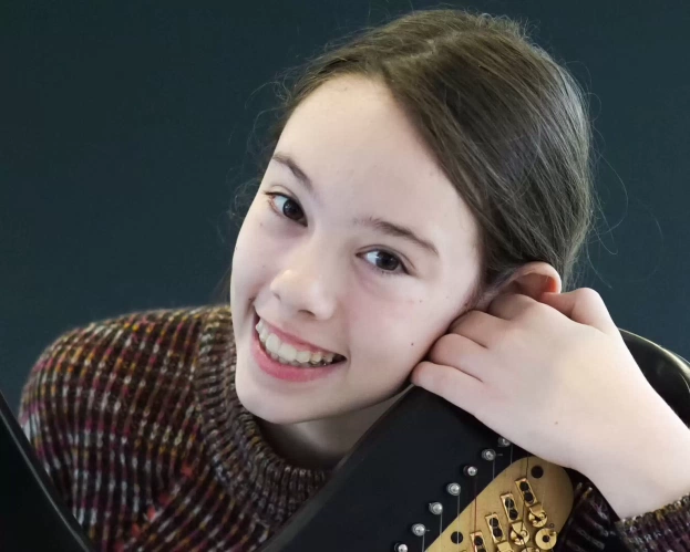 Meisje glimlacht en houdt een elektrische gitaar vast.