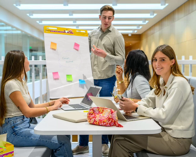 Studenten van de opleiding Finance, Tax and Advice zitten op de trap in het gebouw.