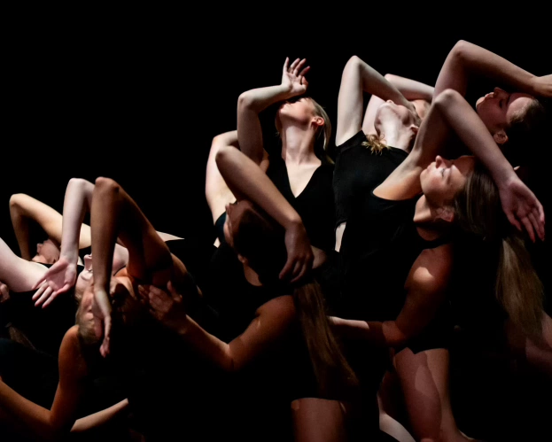 Groep dansers voert samen een expressieve choreografie.